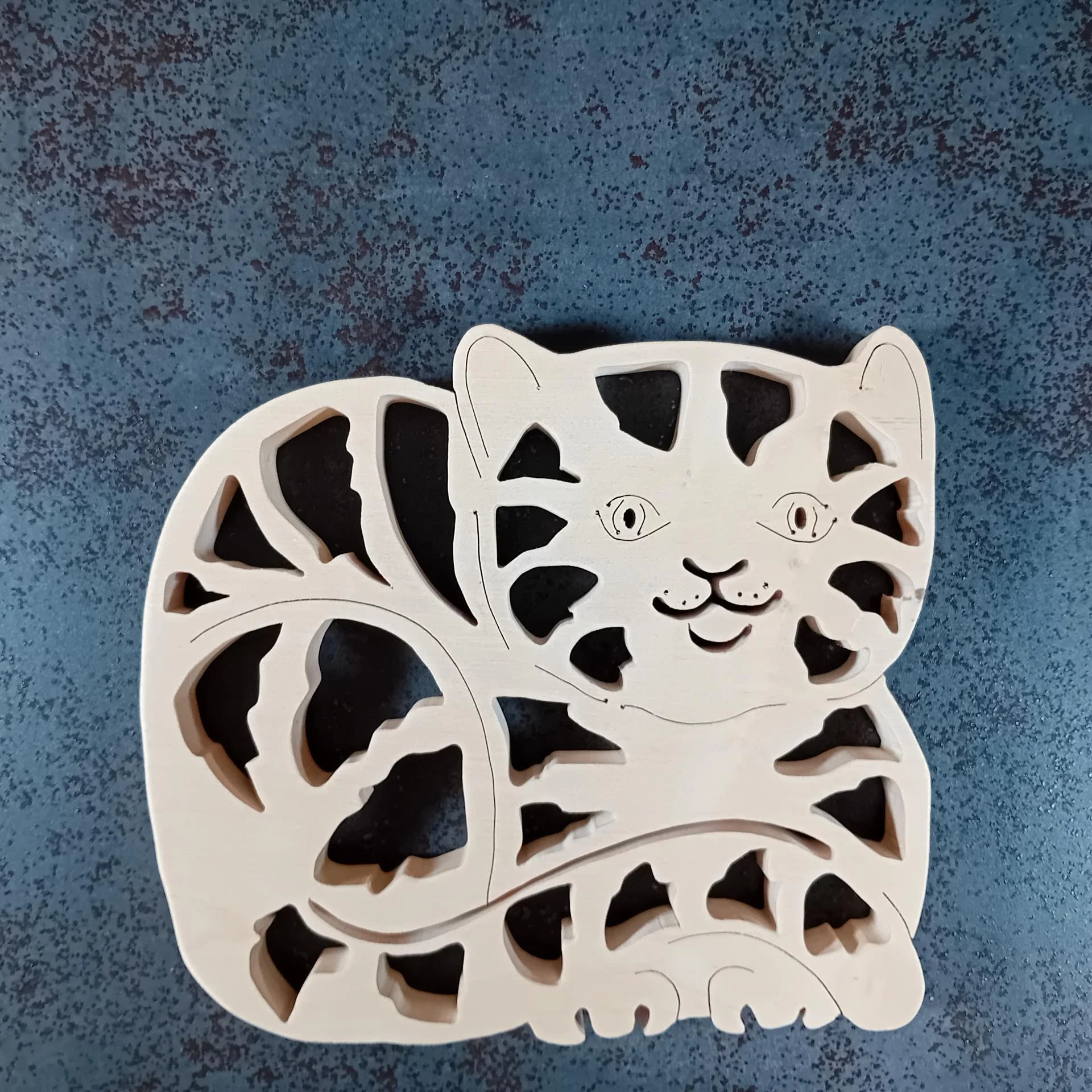 Décoration en bois découpée à la main en chantournage représentant un chat couché. Technique de la dentelle.